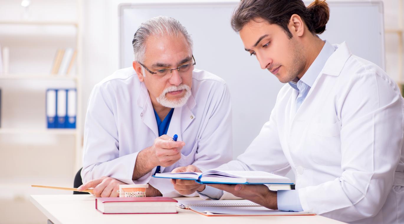 two physicians reading books at a desk